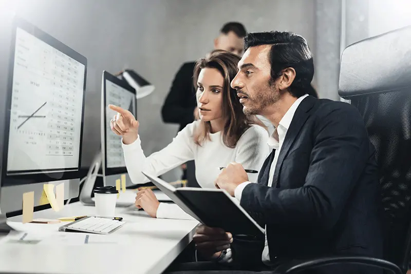 Business colleagues looking at stats on computer