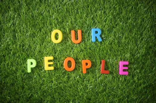 Colorful letters spelling our people on green grass background