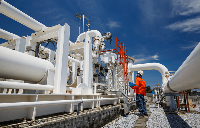 Male worker inspecting steel pipes at refinery
