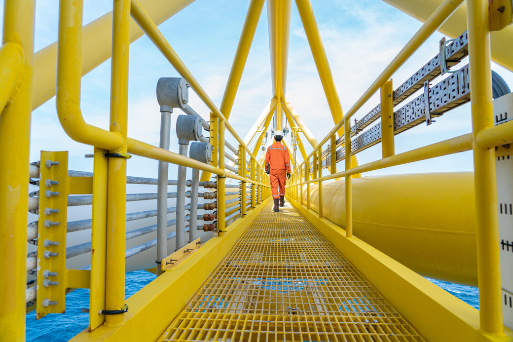 Production operator walking on offshore oil and gas central processing