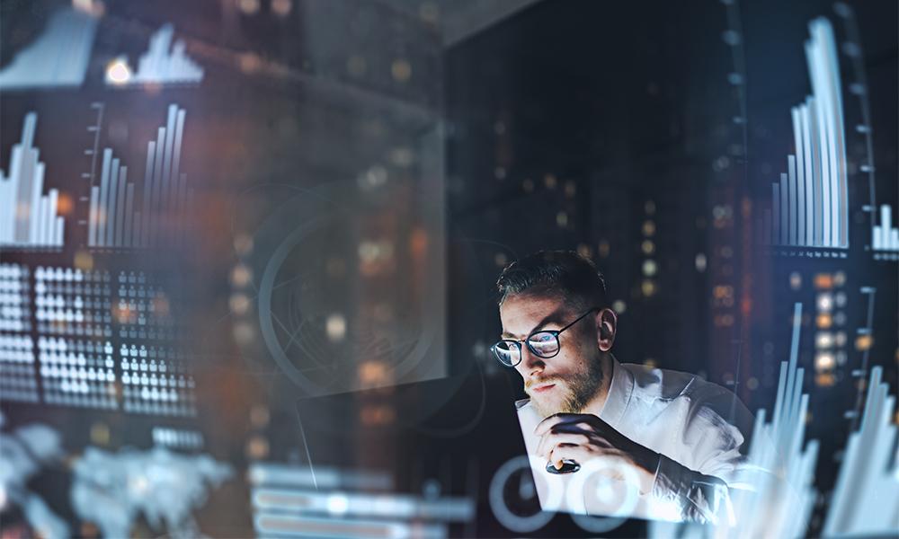 man at computer with digital graphs overlay