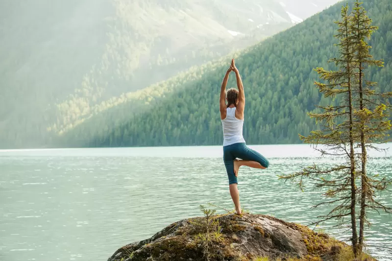 Woman practicing yoga at mountain lake