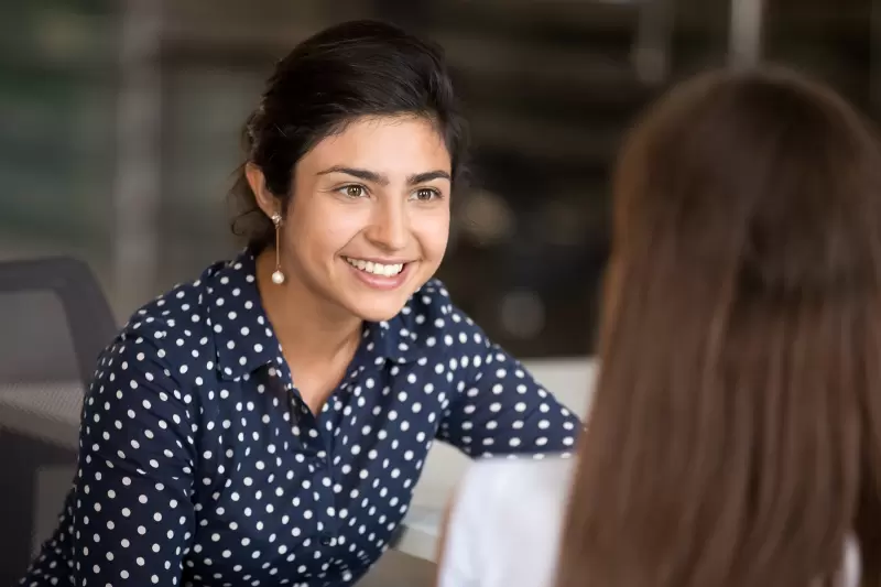 woman talking with colleague sitting at desk